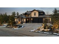 Beautiful two story home with dark colored three car garage and well manicured lawn with stone features at 1803 Avenida Del Sol, Castle Rock, CO 80104