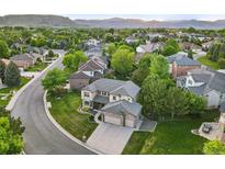 Beautiful aerial view of a suburban home with a well-manicured lawn and a tree-lined street surrounded by lush greenery at 5683 Fig Way, Arvada, CO 80002