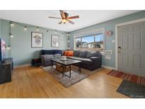 Cozy living room featuring a large gray sofa, stylish lighting, and hardwood floors at 1530 W Berkeley Pl, Denver, CO 80221