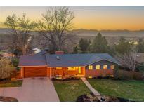A charming single-Gathering home with a brick facade, attached garage, manicured lawn, and mountain views at sunset at 2005 Tabor Dr, Lakewood, CO 80215