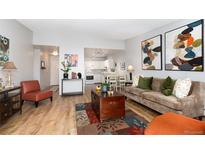 Cozy living room featuring hardwood floors, a comfortable sofa, and an open layout to the modern kitchen and dining area at 3082 S Wheeling Way # 410, Aurora, CO 80014