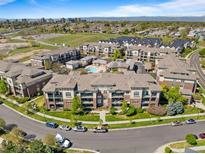 Stunning aerial view of a condo community with lush landscaping, pool, and city skyline in the background at 3865 S Dayton St # 105, Aurora, CO 80014
