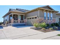 Charming home showcasing a stone and siding exterior with a covered front porch and attached two-car garage at 2012 Sagerock Dr, Castle Pines, CO 80108