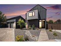 Modern home featuring dark siding, a landscaped yard with a rock pathway, and a detached garage at 3057 S University Cir, Englewood, CO 80113