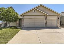 Charming home featuring a three-car garage, well-maintained lawn, mature tree, and neutral-toned exterior at 11014 Callaway Rd, Parker, CO 80138