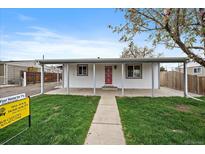 Charming single-story home with a covered porch and a well-maintained front yard at 7460 Krameria Dr, Commerce City, CO 80022