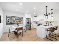 Bright kitchen featuring stainless steel appliances, white cabinetry, eat-in dining area, and hardwood floors at 2355 Ivanhoe St, Denver, CO 80207