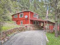 Charming red home with stone foundation and covered parking in a serene wooded setting at 6837 S Brook Forest Rd, Evergreen, CO 80439