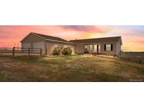 Charming ranch home with an attached two-car garage and landscaped front yard, set against a beautiful sunset backdrop at 13640 County Road 182, Bennett, CO 80102