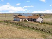 Ranch style home with attached garage and backyard with wooden fence sitting on a grassy lot at 13640 County Road 182, Bennett, CO 80102