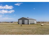 Modern gray outbuilding features two bay doors, metal roof and gray siding with plenty of space and possibilities at 13640 County Road 182, Bennett, CO 80102