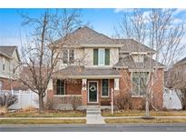 Charming two-story home with brick and siding exterior, a covered porch, and well-maintained landscaping at 1073 Roslyn Ct, Denver, CO 80230