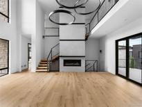 Bright, open-concept living room features a modern fireplace, hardwood floors, and an open staircase to the upper level at 5258 Lions Paw St, Castle Rock, CO 80104