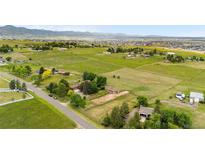 Expansive aerial view of acreage with lush green pastures, scattered trees and mountain views in the distance at 7583 W Trail South Dr, Littleton, CO 80125