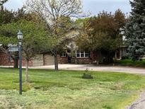 Lovely two-story brick home with attached two-car garage on spacious, tree-filled lot at 7583 W Trail South Dr, Littleton, CO 80125