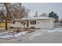 Charming single-story home with brick exterior, attached garage, and landscaped front yard during winter at 6300 Janice Way, Arvada, CO 80004
