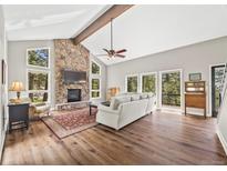 Inviting living room with stone fireplace, vaulted ceilings, wood floors, and bright windows at 30866 Kings Valley Way, Conifer, CO 80433