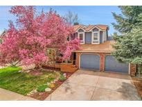 Charming two-story home with a beautiful blooming tree in the front yard and a two car garage at 12718 W 84Th Dr, Arvada, CO 80005