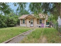 Charming single-story home with a quaint front porch and overgrown lawn at 1340 Iola St, Aurora, CO 80010