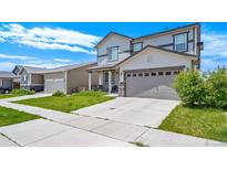 Two-story home with a two-car garage, gray siding and stone accents on the front porch columns at 9923 Truckee St, Commerce City, CO 80022