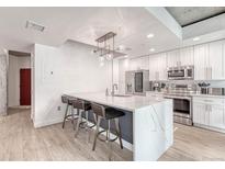 Modern kitchen with stainless steel appliances, a large marble island, and stylish pendant lighting at 1700 Bassett St # 101, Denver, CO 80202