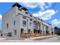 Contemporary townhomes featuring rooftop decks and modern exteriors, with grey siding, black trim, and wood privacy fences at 3520 W Conejos Pl # 14, Denver, CO 80204