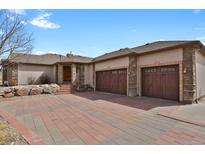 Spacious home exterior with stone accents, brick driveway, and attached two car garage at 5265 Club Ct, Larkspur, CO 80118