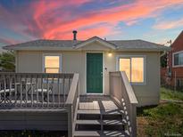 Charming home featuring a cozy front deck, green door, and serene sunset hues at 3134 W Center Ave, Denver, CO 80219