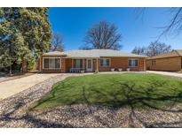 Charming brick home features a well-manicured lawn and classic architectural details at 938 Racine St, Aurora, CO 80011