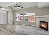 Bright living room with fireplace, ceiling fan, wood floors, and large windows at 14308 E Whitaker Pl # 114, Aurora, CO 80015