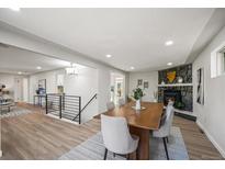 Bright dining room features a wood table, modern light fixture, and a stone fireplace at 8318 Benton Way, Arvada, CO 80003