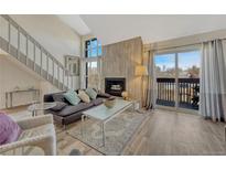 Bright living room with vaulted ceilings, wood accent wall, fireplace and access to a private balcony at 701 Harlan St # E72, Lakewood, CO 80214