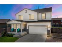 Charming two-story home showcasing a well-maintained lawn, inviting porch, and an attached two-car garage at 47300 Clover Ave, Bennett, CO 80102