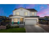 Charming two-story home boasts a cozy front porch, attached two-car garage and well-maintained lawn at 47300 Clover Ave, Bennett, CO 80102
