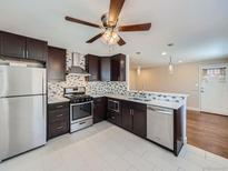 Updated kitchen features stainless appliances, dark wood cabinets, and tile backsplash at 4423 W Tennessee Ave, Denver, CO 80219