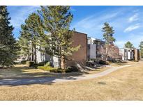 Attractive condo building with manicured landscaping, mature trees, and convenient walkway in front at 1300 Golden Cir # 111, Golden, CO 80401