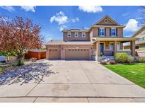 Inviting two-story home featuring a three-car garage, covered front porch, and well-maintained landscaping at 25262 E 2Nd Pl, Aurora, CO 80018