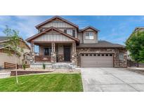 Charming two-story home featuring stone accents, a covered porch, a well-manicured lawn, and an attached two-car garage at 22583 E Union Cir, Aurora, CO 80015