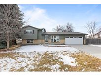 Ranch style home with attached garage and snow-covered yard at 446 Dione Pl, Lone Tree, CO 80124