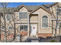 Charming townhome featuring beige siding, brick accents, and a welcoming front door with festive wreath at 6845 S Webster St # G, Littleton, CO 80128