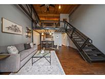 Spacious open-concept living room with high ceilings, hardwood floors, and modern staircase to loft area at 1111 Osage St # 23, Denver, CO 80204