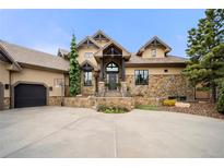 Stunning home with stone accents, beautiful landscaping, and a spacious driveway leading to an attached garage at 5886 Amber Ridge Dr, Castle Pines, CO 80108