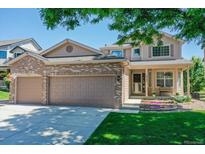 Charming two-story home with a well-manicured lawn, flower beds, and a spacious two car garage at 14191 W Amherst Ave, Lakewood, CO 80228