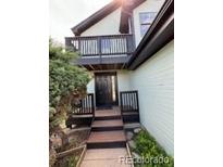 Inviting home entrance with a striking black door, complemented by a dark wood balcony, and wood stairs at 4362 Denmark Ct, Denver, CO 80239