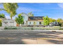 Charming two-story home featuring a white picket fence, solar panels, and a detached garage at 8501 W 52Nd Ave, Arvada, CO 80002