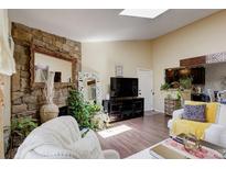 Bright living room with stone fireplace, skylight, and hardwood floors for a warm, inviting ambiance at 10150 E Virginia Ave # 18-302, Denver, CO 80247