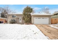 Charming single Gathering home featuring a two-car garage and inviting front yard covered in snow at 2963 S Ivan Way, Denver, CO 80227