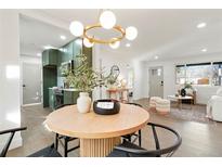 Bright dining area features modern light fixture, wood floors, and green cabinetry at 211 Newport St, Denver, CO 80220