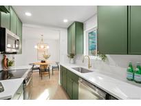 Bright kitchen featuring green cabinets, white countertops, stainless steel appliances and a view into the dining area at 211 Newport St, Denver, CO 80220