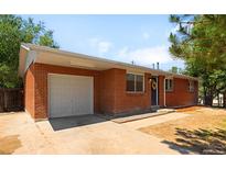 Charming brick home featuring an attached garage, a well-maintained lawn and inviting curb appeal at 5993 Oneida St, Commerce City, CO 80022